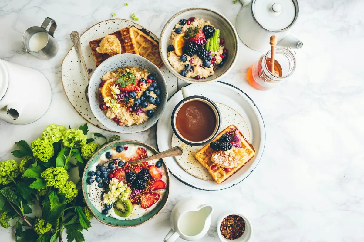 Breakfast spread with yogurt bowls, waffles, fruit and coffee